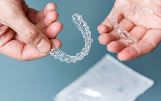 two hands holding aligners